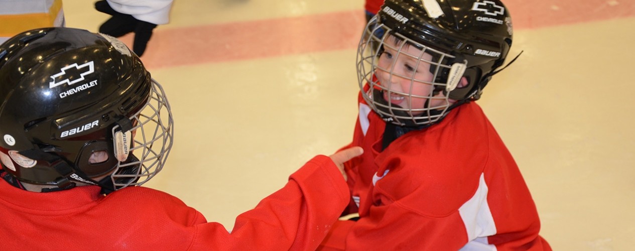 Young Kid On Hockey Rink Sticking His Tongue Out At Another Player