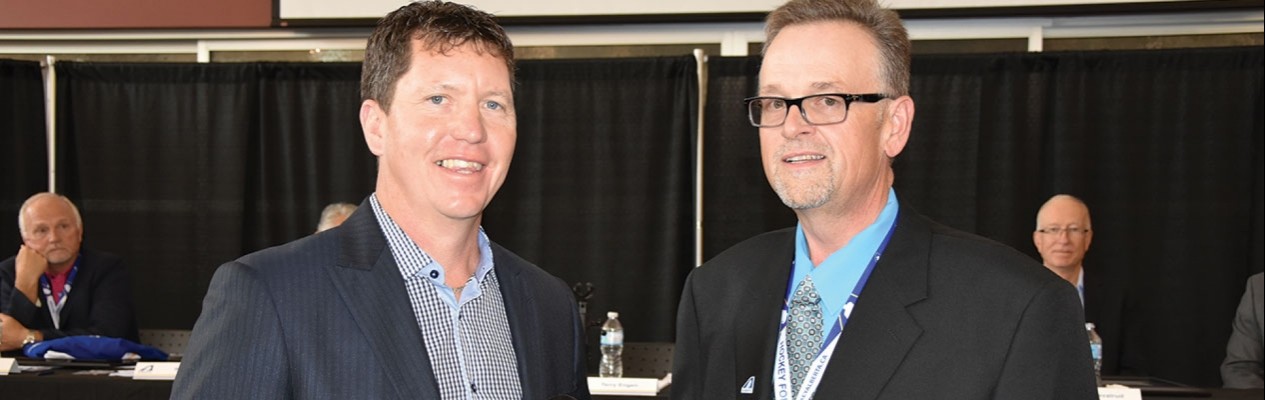 Doug Kinsella (left), accepts the Chairman of the Board award from Terry Engen during Hockey Alberta’s Annual General Meeting